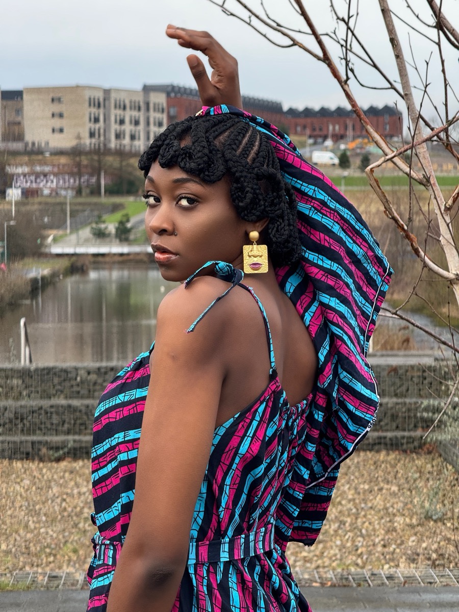 Client with box braids glancing over her shoulder, styled by Hair by Alexy